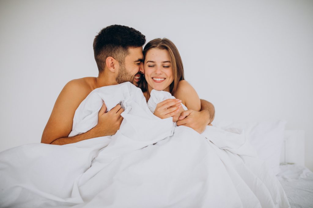 Imagen: Pareja feliz disfrutando de intimidad y conexión en la cama.